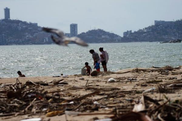 Locals walk on a debris filled beach after Hurricane Otis ripped through Acapulco, Mexico, on Thursday, Oct. 26.